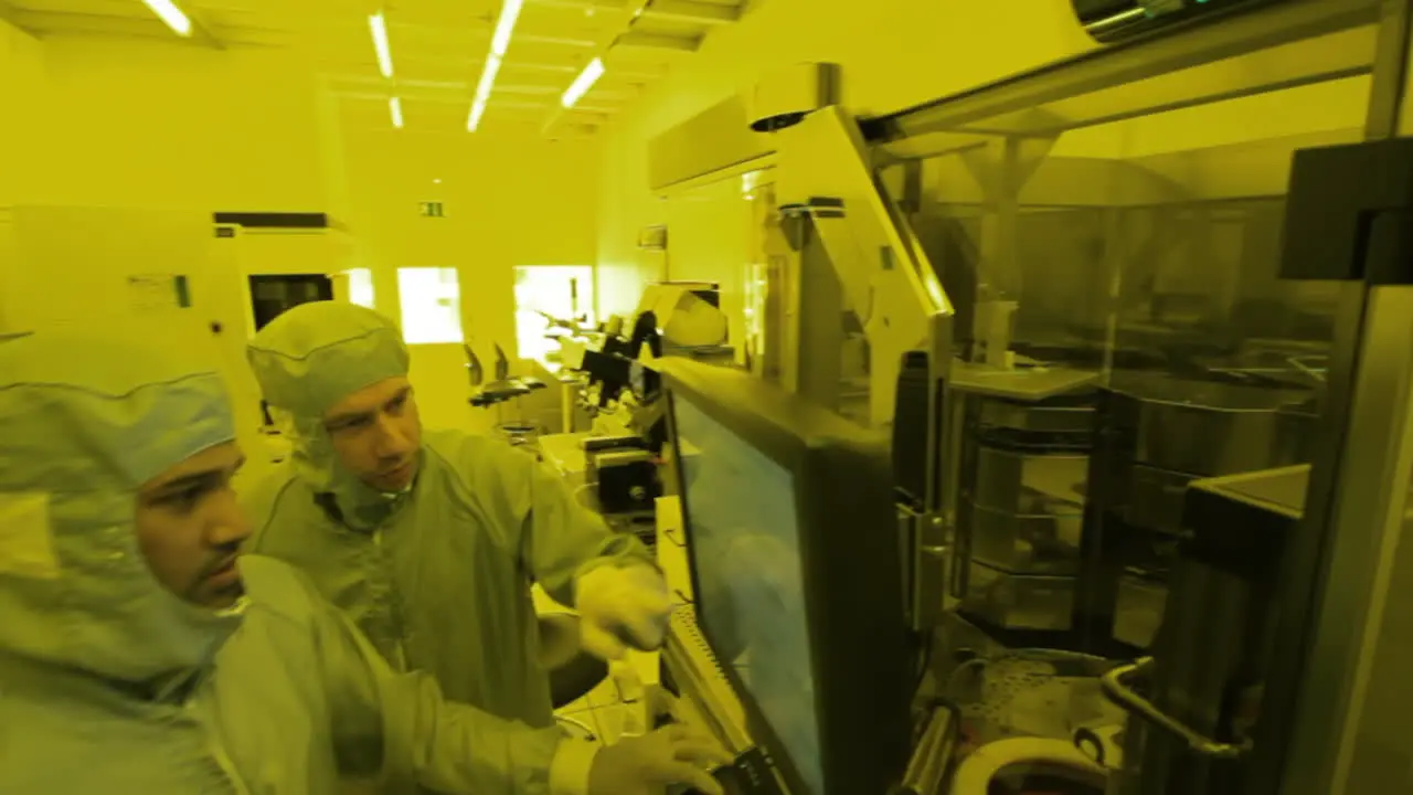 Slow pan to the left of a group of scientists doing experiments in a laboratory and touching a screen