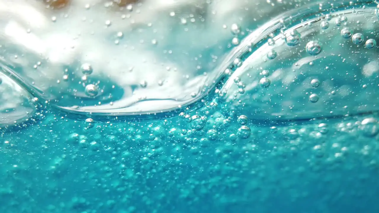 Blue liquid background bubbles move gently within glass container