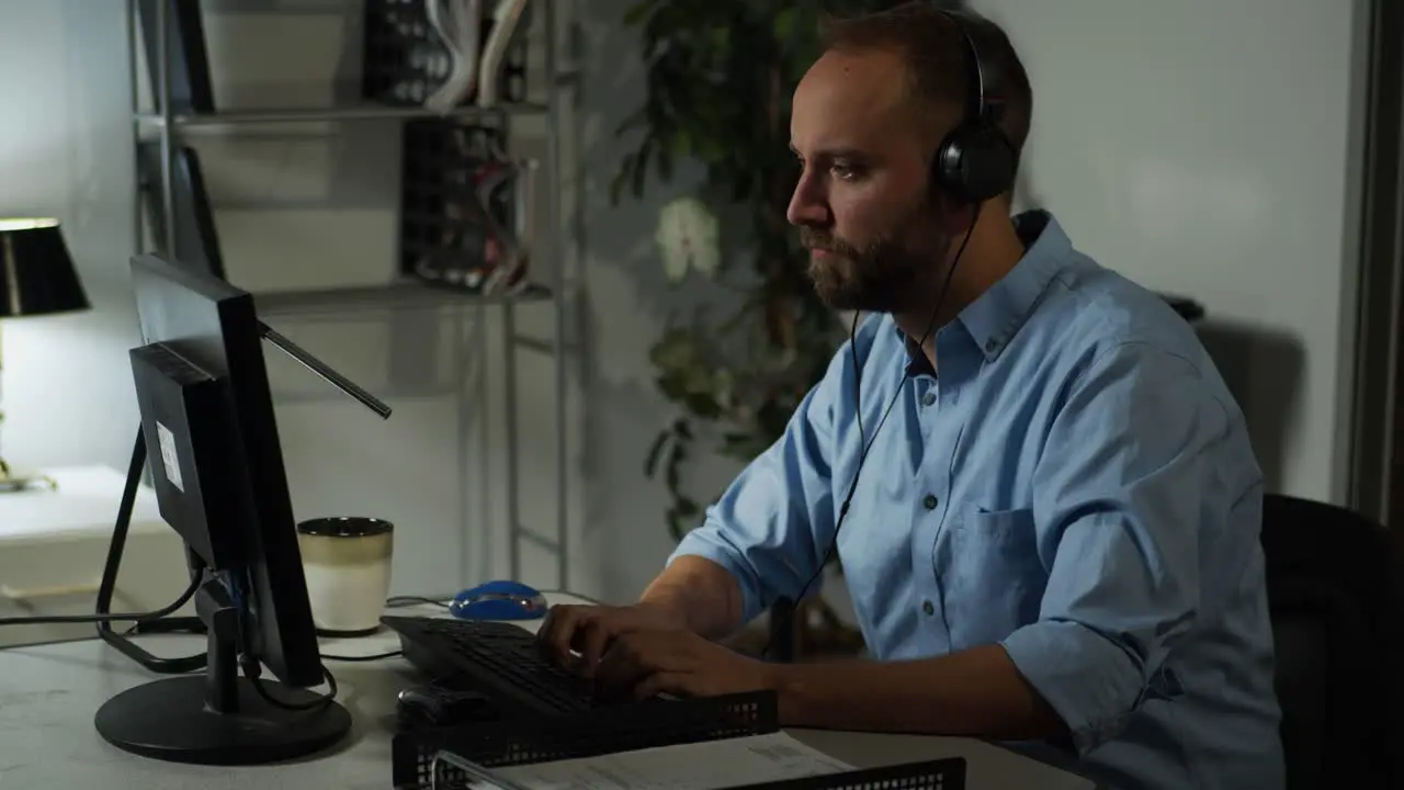 Male office working working late while listening to music on headphones