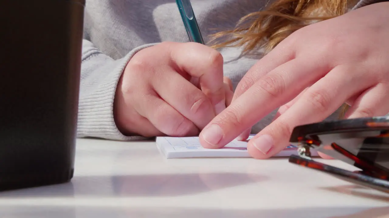 A close-up of hands writing on a score pad during a dice game