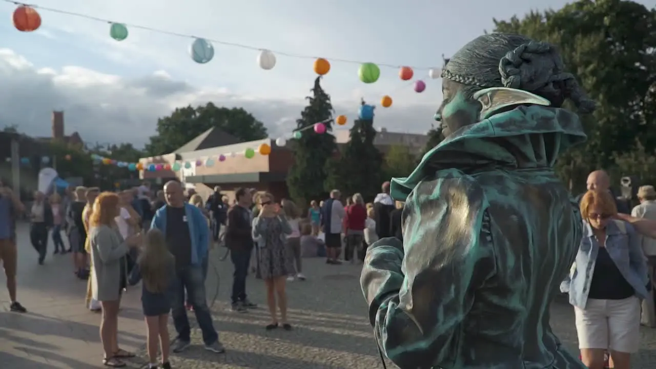 Street artist with green costume smile towards the sun