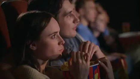 Young couple eating popcorn from one box Fiends couple watching movie