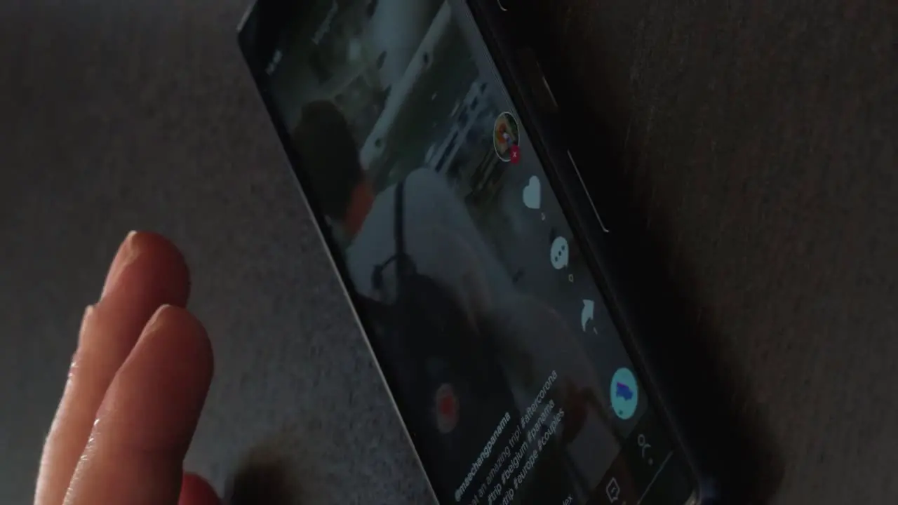 Vertical shot of male hand holding and scrolling mobile phone with TikTok application on the screen