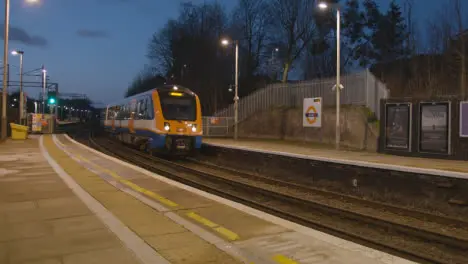 Early Morning Shot Of Commuter Train Arriving At Platform Of Railway Station At In Bushey UK