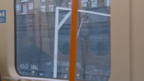 Urban View From Commuter Train Window With Graffiti And Electric Power Lines