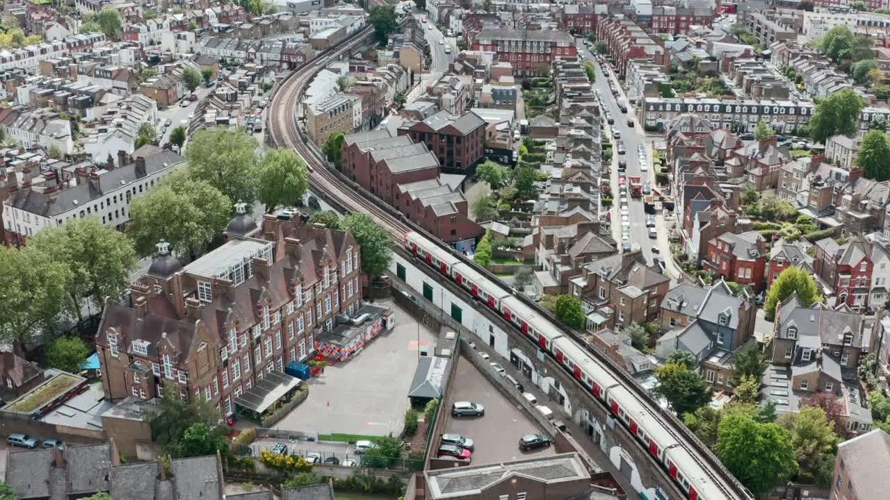 Cinematic drone follow shot of district line train winding through residential London Putney bridge