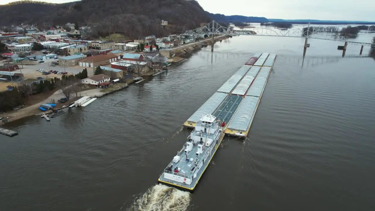 A towboat pushing barges north on the Mississippi River approaches the Black Hawk Bridge at Lansing Iowa