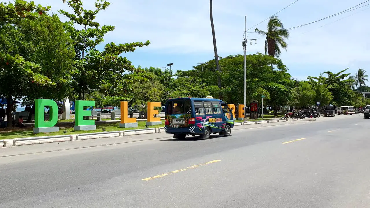 A colourful blue microlet public transport bus on a busy street with popular landmark in the capital city Dili Timor Leste Southeast Asia