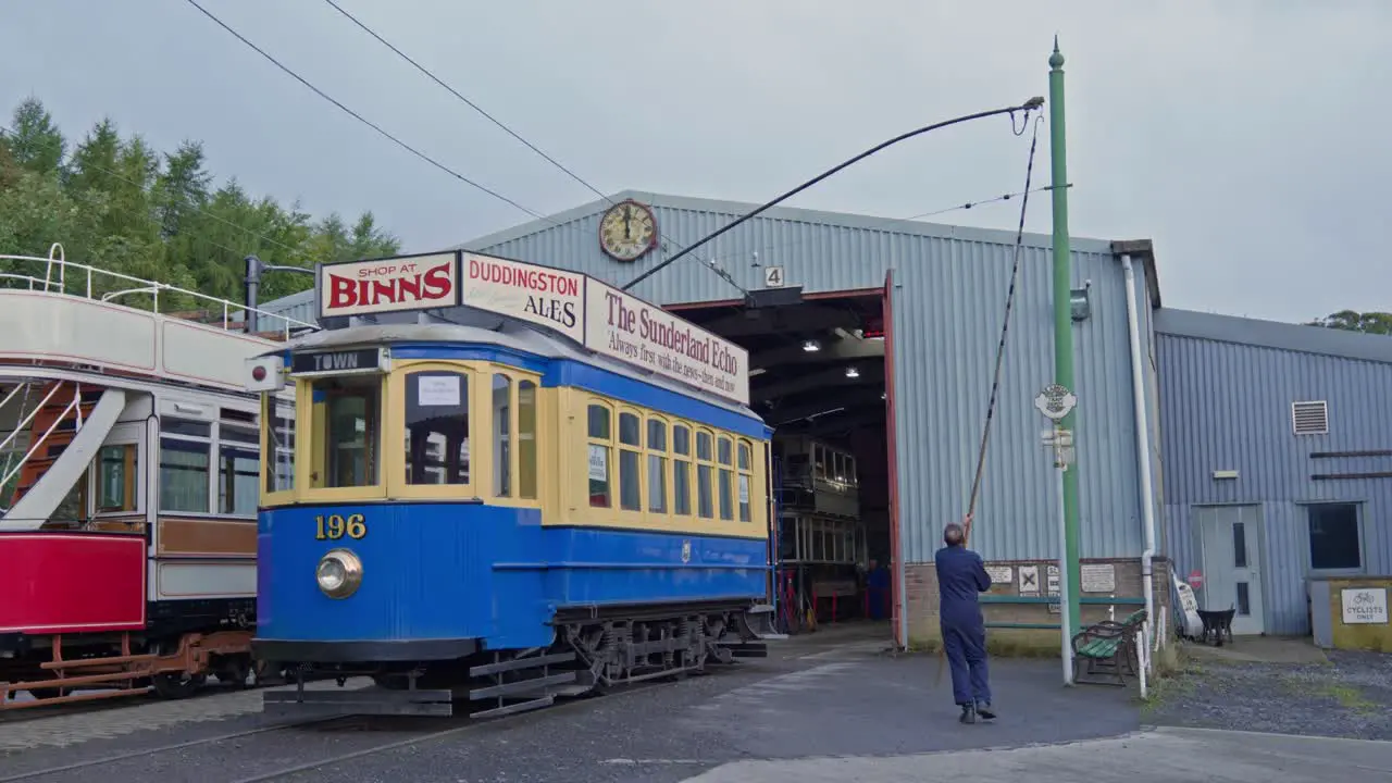 Man changes electrified power cables for vintage passenger tram