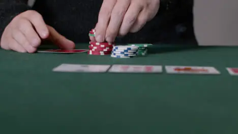 Sliding Shot of Poker Player Checking Cards and Placing Bet