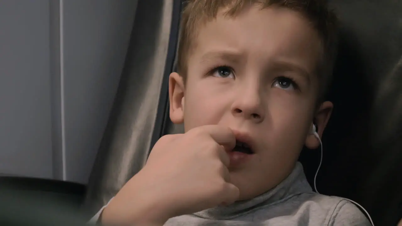 Boy with earphones watching TV in train