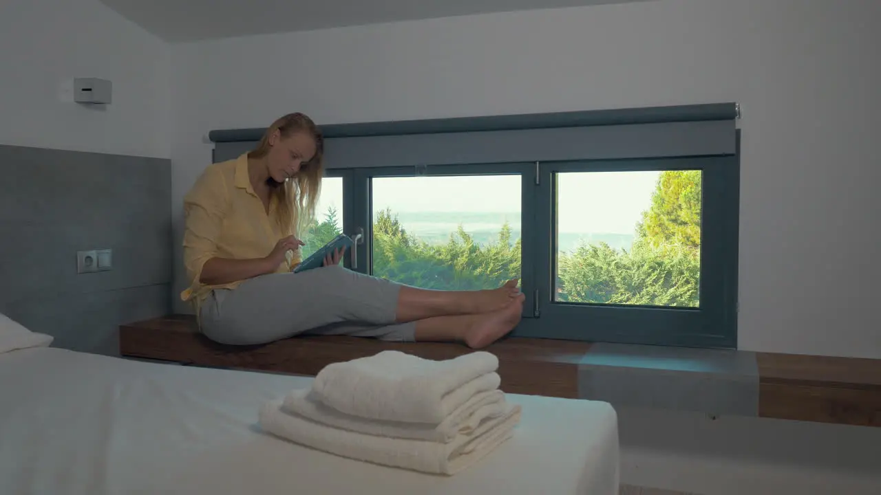 Woman using pad by the window in hotel