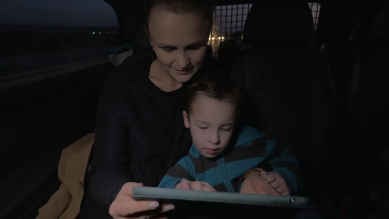 Mother and son playing with touch pad during night car ride