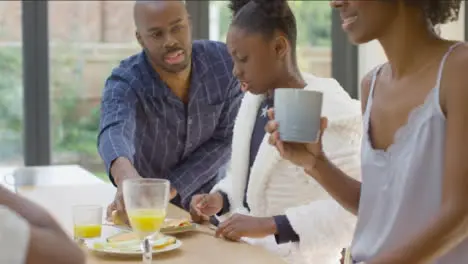 Family Laughing and Talking to One Another Over Breakfast at Kitchen Island