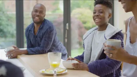 Young Girl Making Her Brother and Parents Laugh During Breakfast