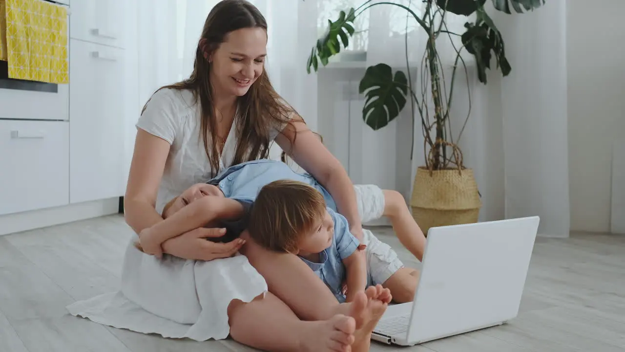 Beautiful modern young family lying on the floor at home and doing something in laptop