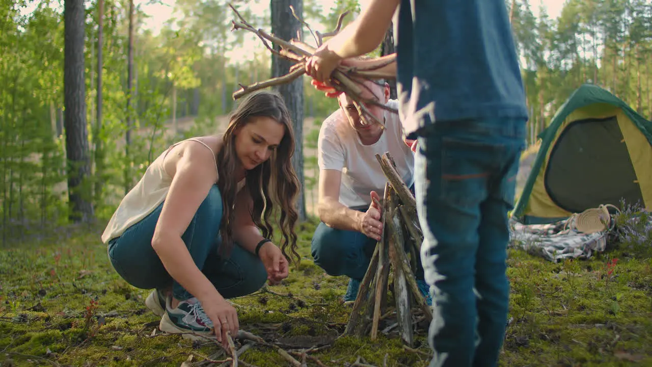 Families in nature together collect and install a fire for cooking Family journey into the woods Hike with a tent and an overnight stay in the woods by the fire