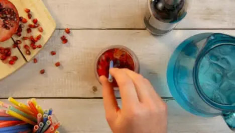 Top View Male Hands Adding Pomegranate Seeds to Drink and Stirring