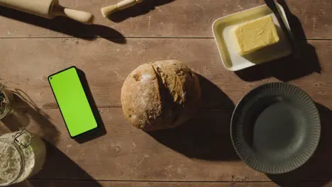 Overhead Shot Of Freshly Baked Loaf Of Bread On Wooden Table With Green Screen Mobile Phone 1