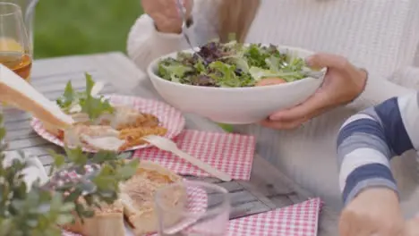 Tracking Shot Over Table of Food as Family Serve It Up During Outdoor Dinner 01