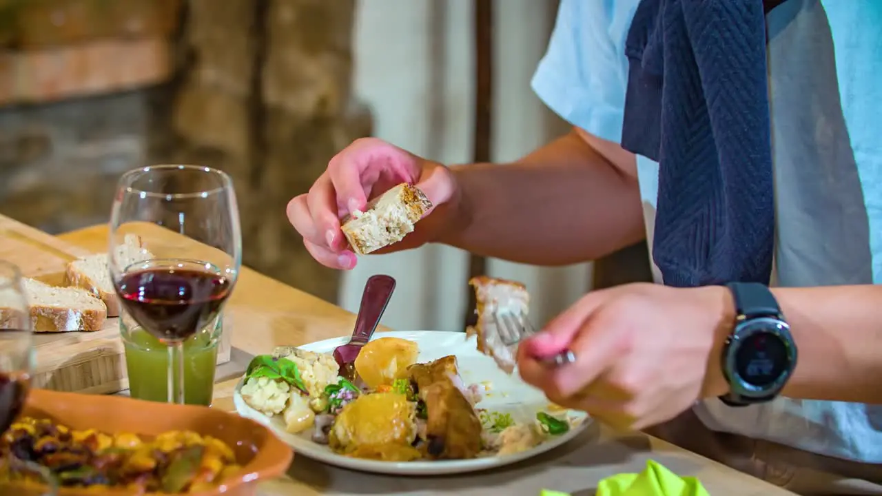 Young man enjoys meal of meat vegetables freshly baked bread and red wine