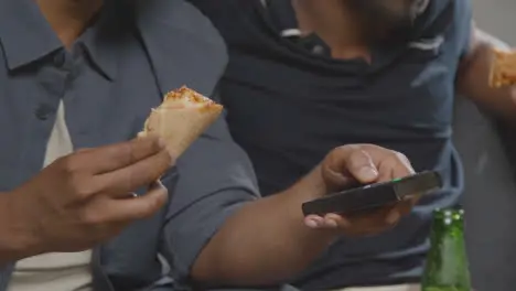 Multi-Cultural Friends Sitting On Sofa At Home Watching TV Eating Takeaway Pizza Delivery 1