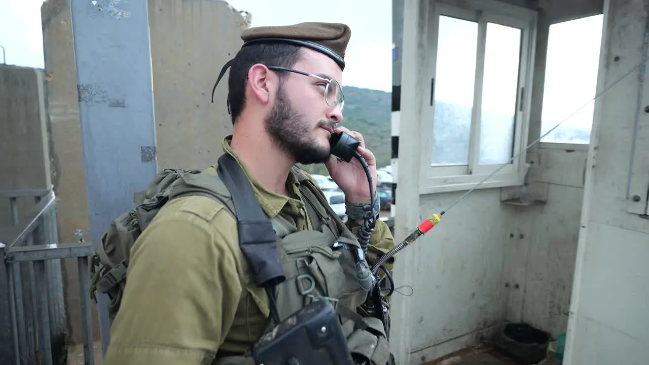 heavily-armed IDF soldier using handheld radio in security checkpoint