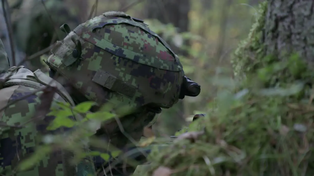 Soldier lying down stalking in forest aiming rifle handheld closeup slow motion