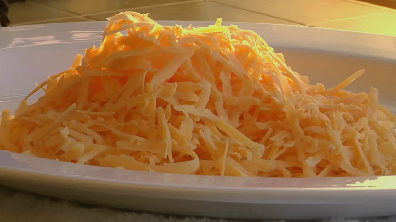 A slow move into grated cheese sitting on the top of steaming scrambled eggs