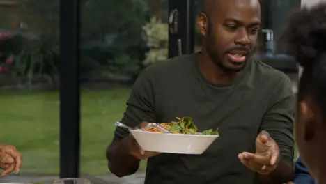 Middle Aged Man Talking to His Son at Dinner Table as They Plate Up Food 