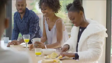 Family Talking and Laughing With One Another Over Breakfast at Kitchen Island