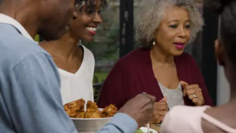 Family Plating Up Food On Their Plates During Evening Meal 