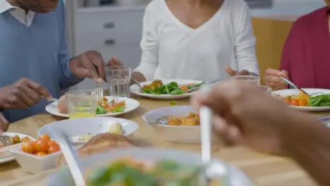 Family Passing Bowls of Food Around the Table During Dinner