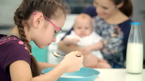 Girl eating breakfast with mother and baby Kid have lunch at kitchen