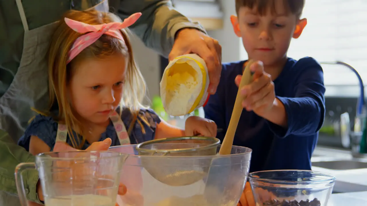 Front view of young Caucasian father and children preparing food in kitchen of comfortable home 4k