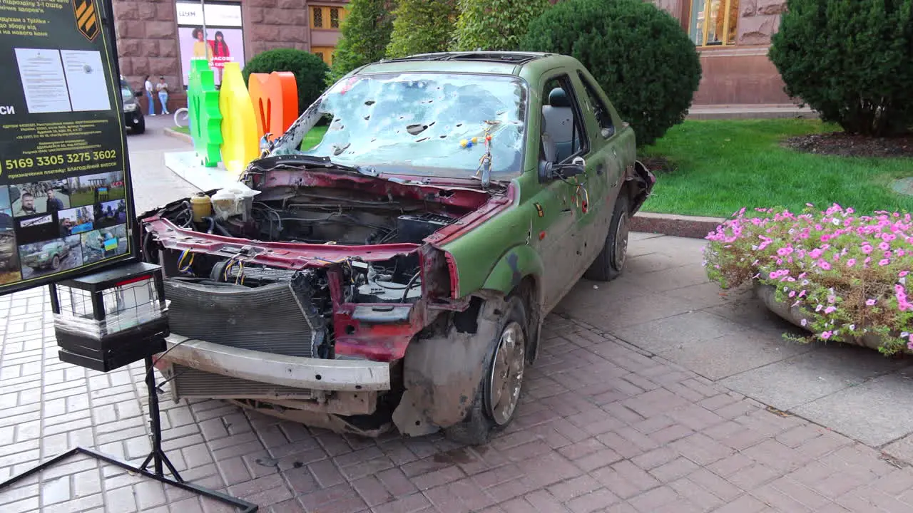 Shelled green car on Khreshchatyk main street from the Russia Ukraine war in Kyiv city center destroyed broken war vehicle in Ukraine 4K shot