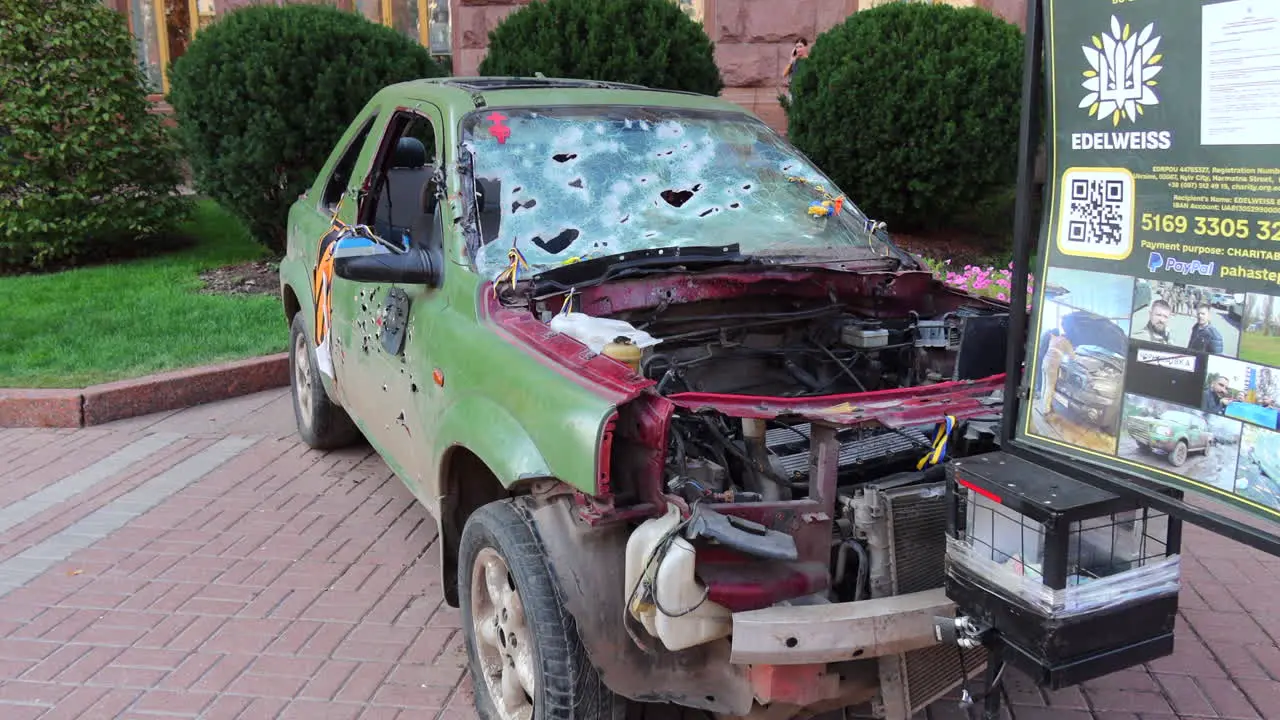 Shelled green car on Khreshchatyk main street from the Russia Ukraine war in Kyiv city capital center destroyed war vehicle in Ukraine 4K shot