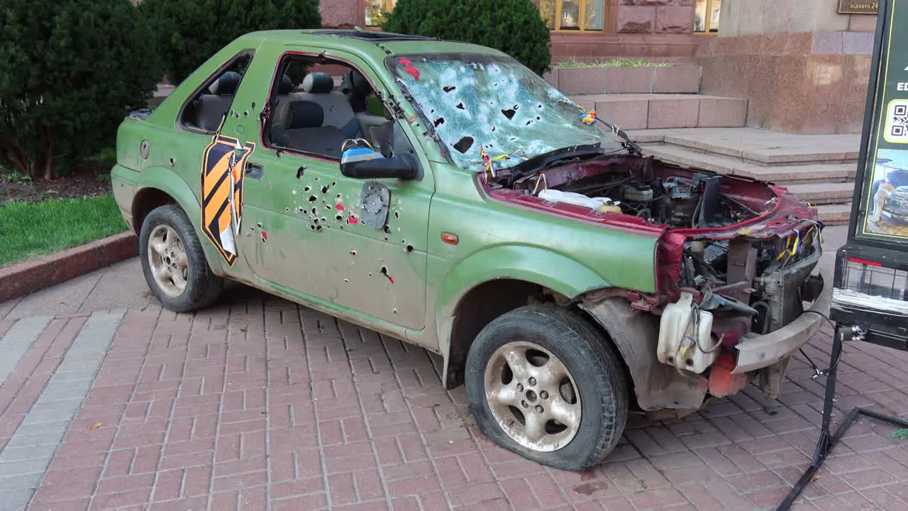 Shelled green car on Khreshchatyk main street from the Russia Ukraine war in Kyiv city center destroyed war vehicle in Ukraine 4K shot