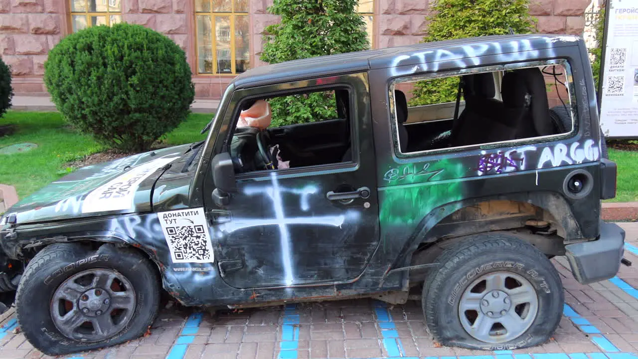 Shelled black car on Khreshchatyk main street from the Russia Ukraine war in Kyiv city center destroyed broken jeep war vehicle in Ukraine 4K shot