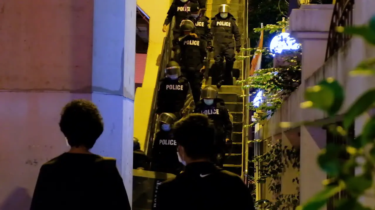 Police walk down stairs at night with protective riot gear and shields before protest