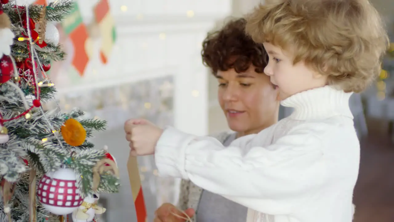 Mom And Little Son Decorating Christmas Tree Together