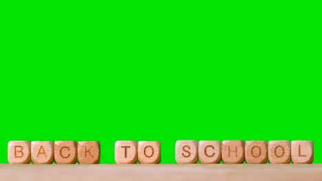 Education Concept With Wooden Letter Cubes Or Dice Spelling Back To School Against Green Screen Background