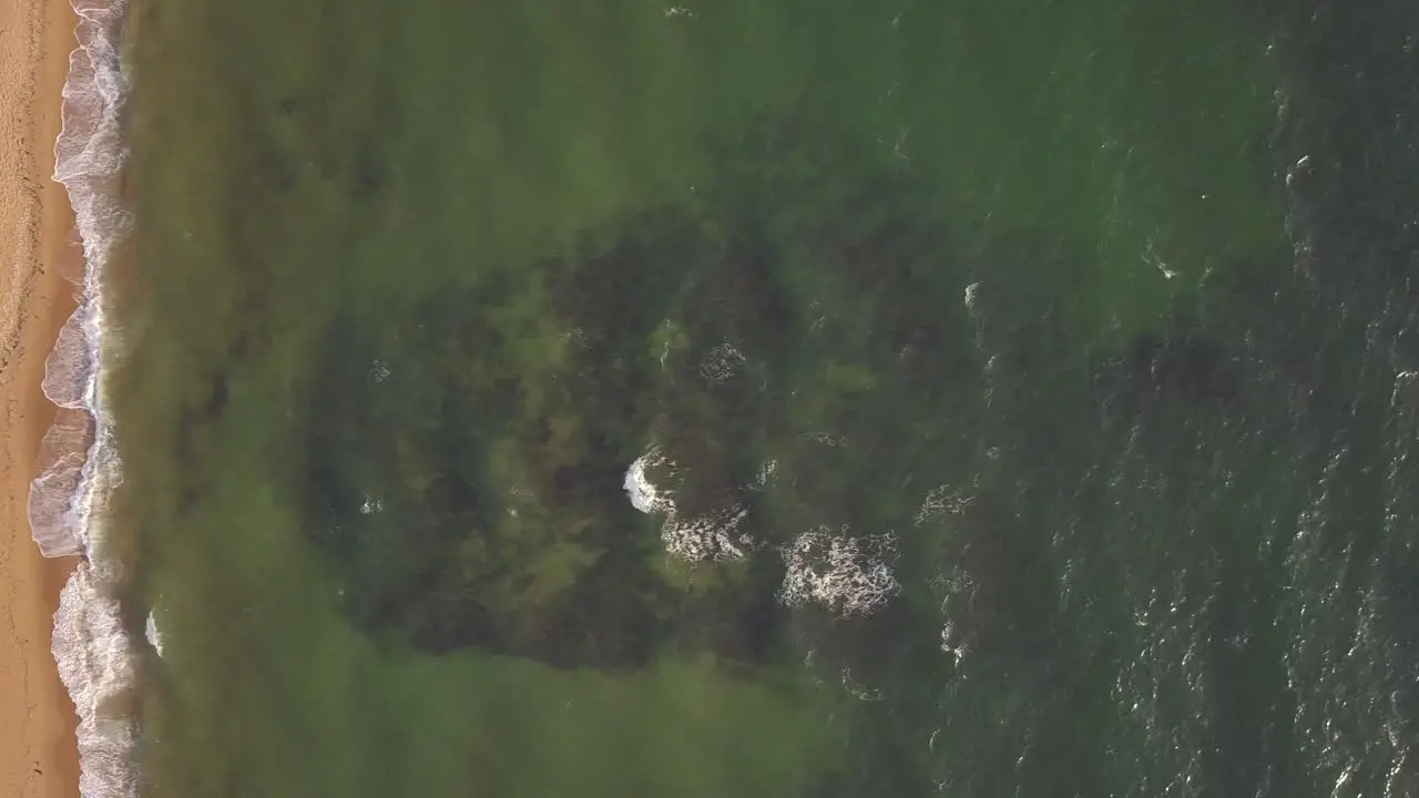 Drone aerial top down view of waves sea ocean at St Kilda beach cam moving right to left Australia Melbourne