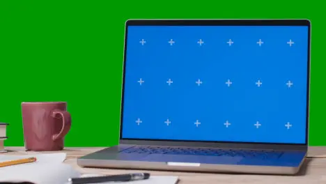 Blue Screen Laptop With Books On Table With Green Screen Background