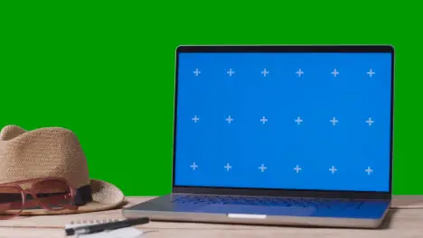 Blue Screen Laptop On Table With Holiday Accessories And Green Screen Background 1