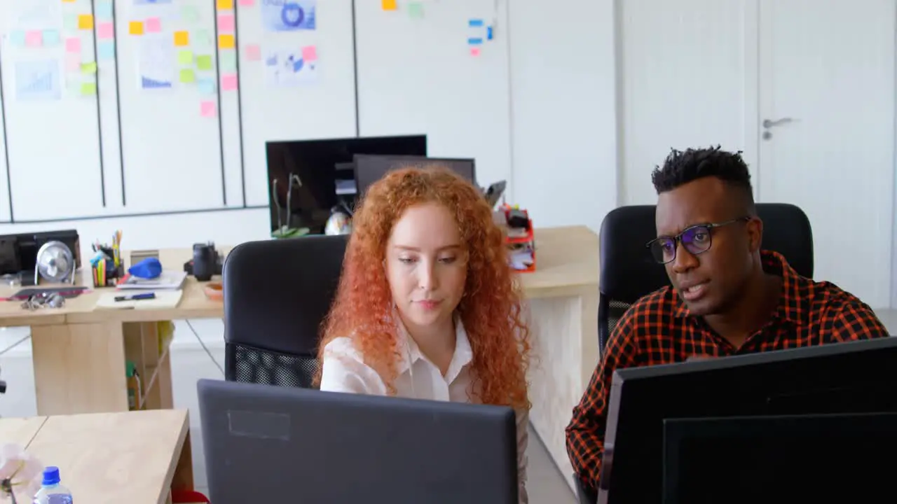 Front view of young cool mixed-race business team planning and sitting at desk in a modern office 4k