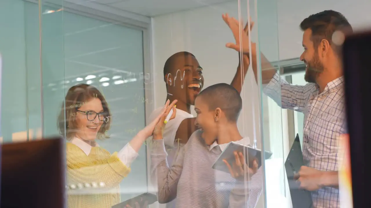 Young mixed race business team discussing over glass board in modern office 4k