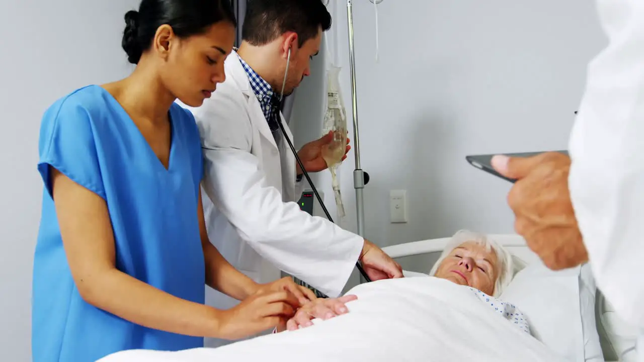 Doctors examining senior patient in ward 