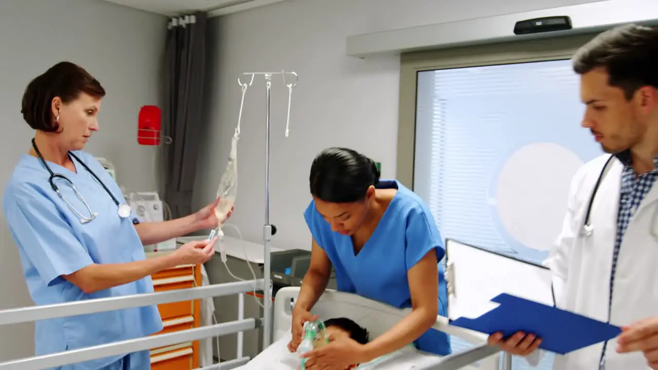 Doctors placing an oxygen mask and adjusting a iv drip to patient in emergency room