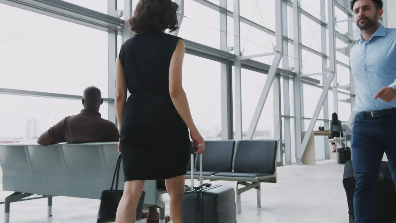 Busy Airport Departure Lounge With Businesspeople Wheeling Luggage At Taking Seats